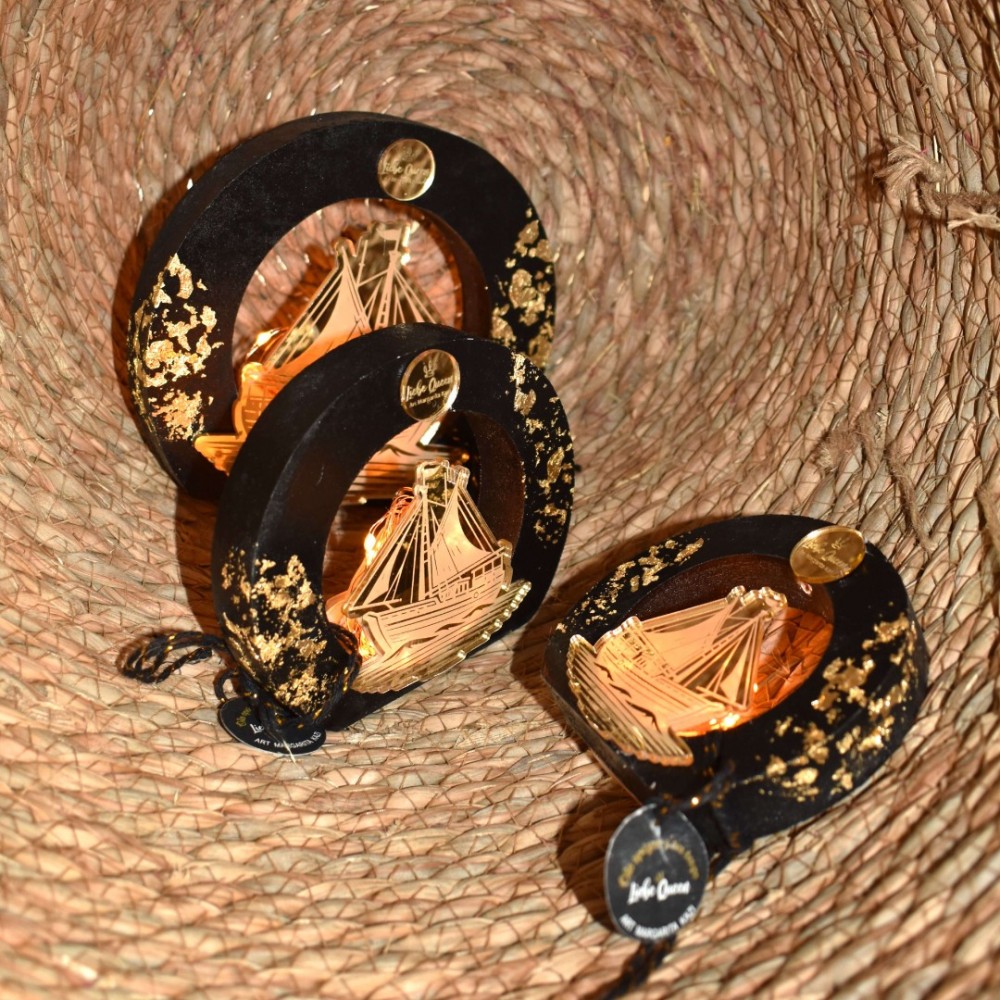 Γούρι καραβάκι χρυσό φωτι΄ζόμενο σε μεσαίο μαύρο ξύλινο κύκλο